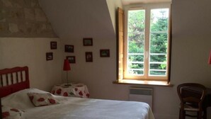 A bedroom with a bed, a chair, a window, and a radiator. - Charming cottage in Chinon forest with private garden (Saint-Benoît-la-Forêt)