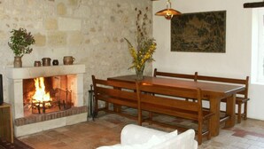 A rustic interior with a stone fireplace, wooden furniture, and a painting on the wall. - Charming cottage in Chinon forest with private garden (Saint-Benoît-la-Forêt)