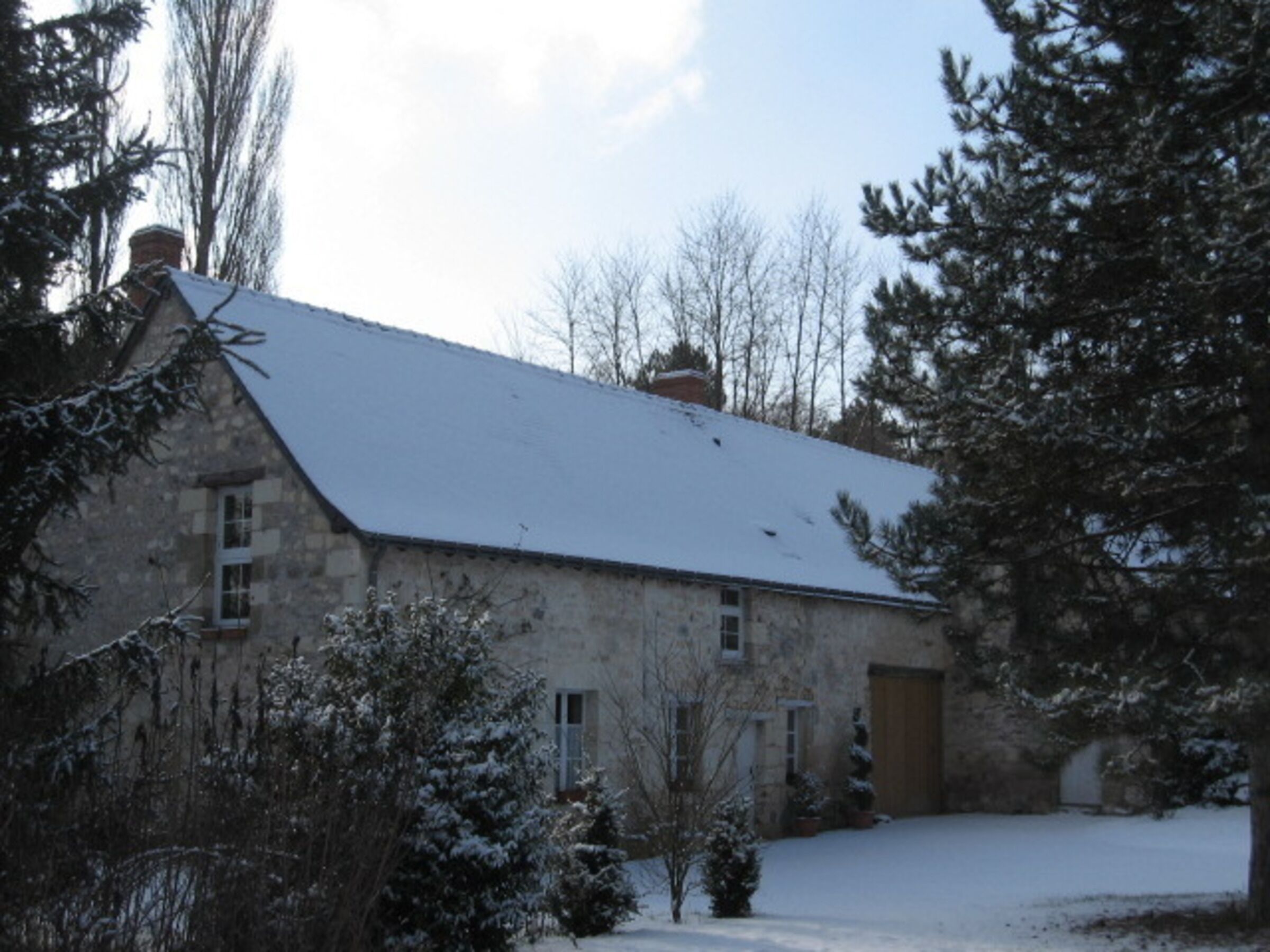 A stone building with a sloped roof, a wooden door, and a snow-covered landscape.