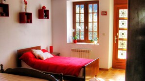 Una camera da letto con un letto, una finestra con piante, un termosifone e una porta con una finestra.