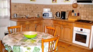 Una cucina con armadietti in legno, un tavolo da pranzo con sedie, un forno a microonde, una macchina per il caffè e un fornello.