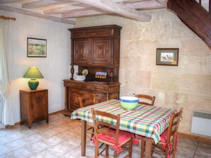 Un comedor con mantel a cuadros, sillas de madera, un armario y una lámpara.