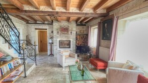 A spacious living room with a stone fireplace, a television, and a comfortable seating area. - Charming 17th-Century Farmhouse with Garden, Terrace, Modern Amenities, and Wi-Fi in Villandry (Villandry)
