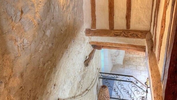 A rustic interior with exposed wooden beams, a stone wall, and a metal staircase. - Charming 17th-Century Farmhouse with Garden, Terrace, Modern Amenities, and Wi-Fi in Villandry (Villandry)