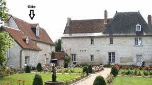 A traditional stone building with a garden pathway leading to a fountain. - Charming 17th-Century Farmhouse with Garden, Terrace, Modern Amenities, and Wi-Fi in Villandry (Villandry)