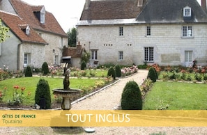 A traditional stone building with a garden pathway leading to a fountain.