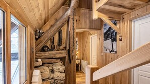Interior de madera con pared de piedra, escalera de madera y un banco.