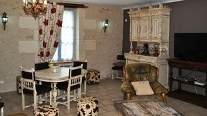 Ein Essbereich mit einem runden Tisch, Stühlen, einer Chandelierleuchtre und einem Schrank mit Fernseher.