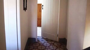 En smal hall med ett mönstrat golv som leder fram till en dörr.