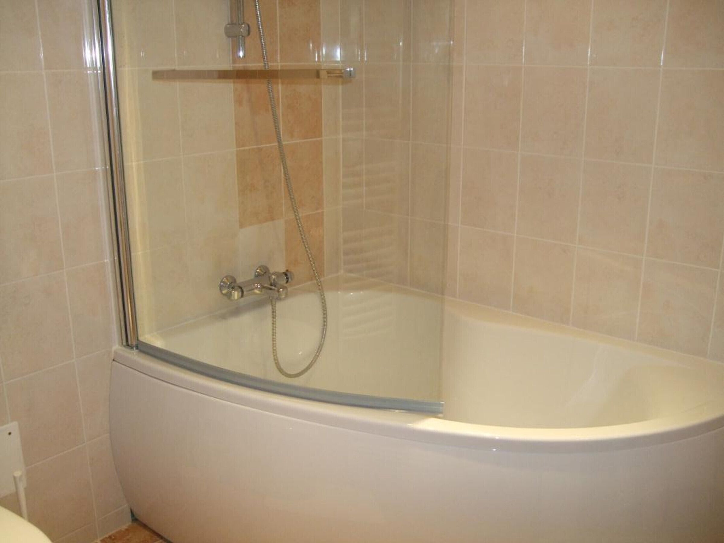 A corner bathroom with a glass-enclosed shower and a white bathtub.