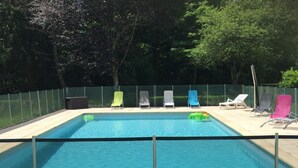 A rectangular swimming pool with a blue water feature, surrounded by a fence.