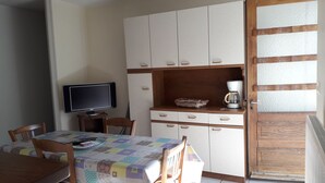 A compact kitchen with a television, a coffee maker, and a table with chairs. - T3 with garden in mini farm 10 minutes from Thonon and Lake Leman (Allinges)