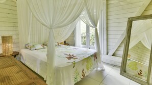 A room with a bed under a canopy, a window, and a mirror.