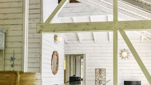 A rustic interior with a wooden bar area, wooden stools, and a high ceiling with exposed beams.