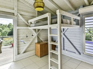 Ein Zimmer mit einem Etagenbett, einer Holzkiste und einer Pendelleuchte.