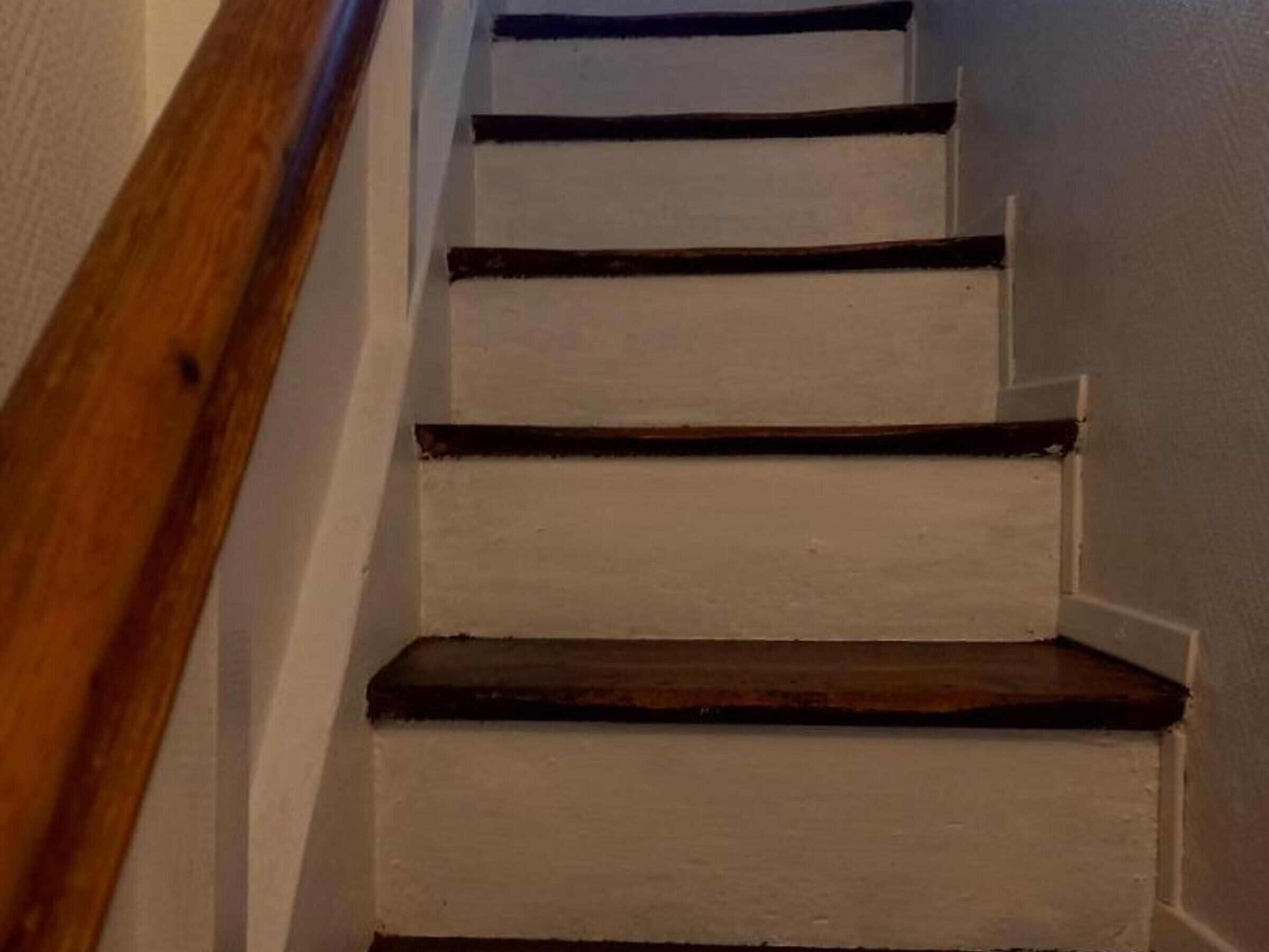 A staircase with wooden steps and white walls.