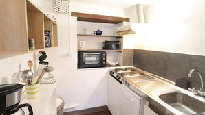 A compact kitchen with a microwave, toaster, and sink. - Charming family apartment in central Saint-Vaast-la-Hougue with wifi (Saint-Vaast-la-Hougue)