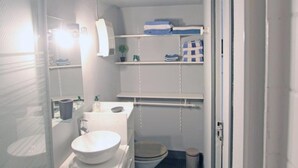 A compact bathroom with a toilet, sink, and shelves for toiletries. - Charming family apartment in central Saint-Vaast-la-Hougue with wifi (Saint-Vaast-la-Hougue)