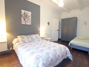 A bedroom with a bed, a chair, a wardrobe, and a door. - Charming family apartment in central Saint-Vaast-la-Hougue with wifi (Saint-Vaast-la-Hougue)