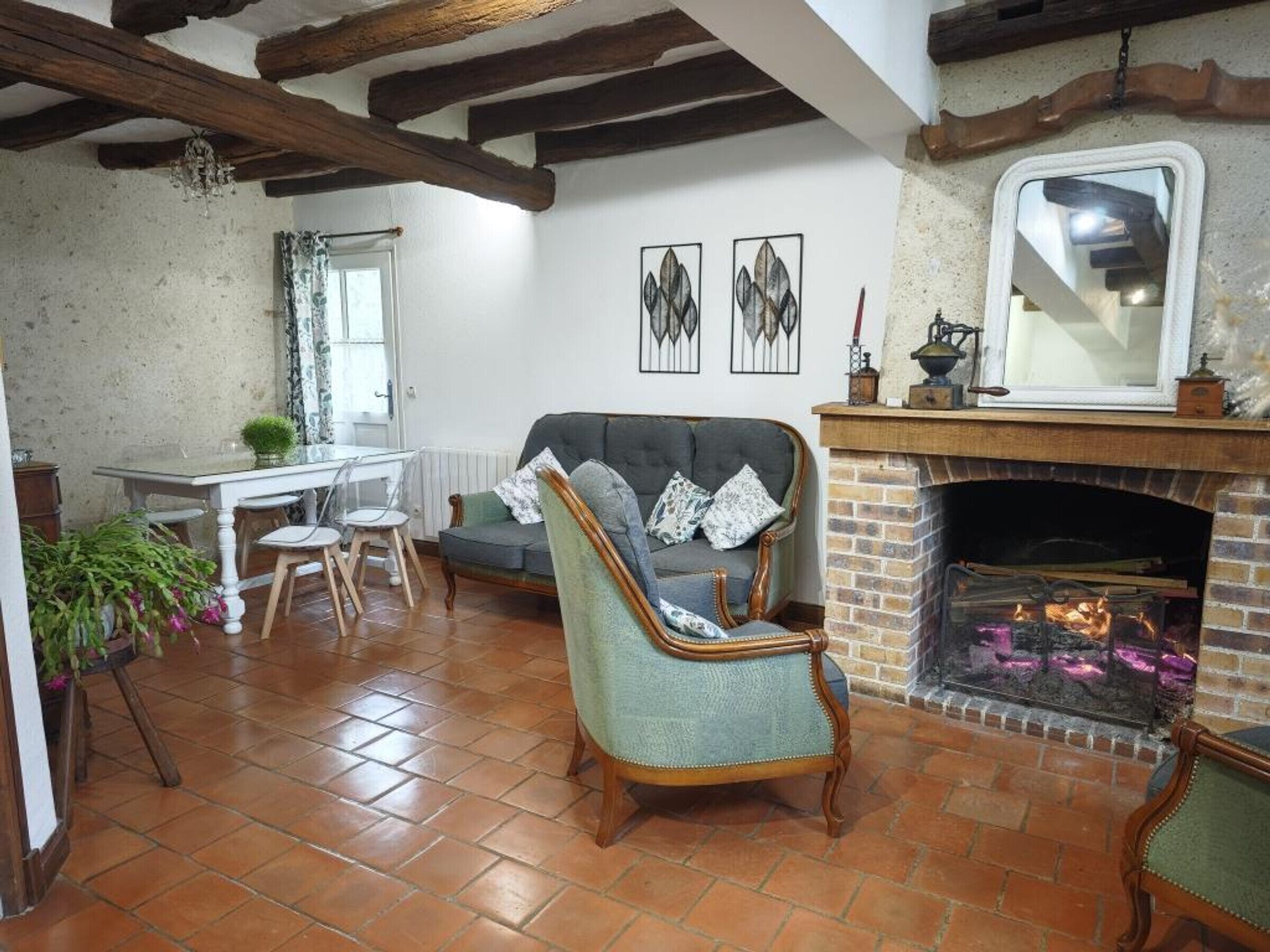 A cozy living room with a fireplace, a dining area, and a window with curtains.