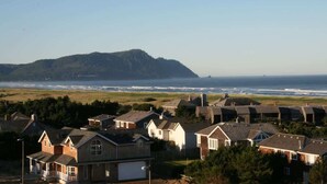 Un área residencial costera con casas, vista al océano y una colina al fondo.