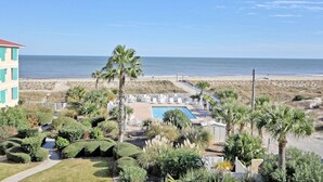 A beachfront hotel with a pool, palm trees, and a view of the ocean. - Desoto unit 302, Luxury 3 Bedroom with Amazing Ocean View  (Tybee Island)