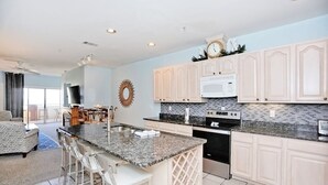 A modern kitchen with white cabinetry, a granite countertop, and stainless steel appliances. - Desoto unit 302, Luxury 3 Bedroom with Amazing Ocean View  (Tybee Island)