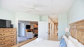 A bedroom with a bed, a wooden dresser, a television, and a ceiling fan. - Desoto unit 302, Luxury 3 Bedroom with Amazing Ocean View  (Tybee Island)