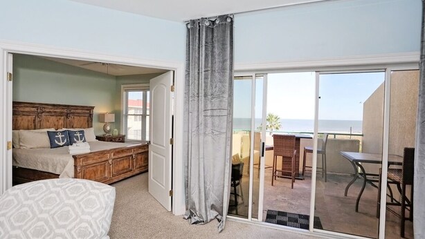 A bedroom with a bed, nightstands, and a view of the balcony. - Desoto unit 302, Luxury 3 Bedroom with Amazing Ocean View  (Tybee Island)