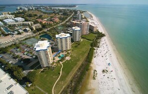 An aerial view of a coastal area with high-rise buildings, a beach, and a marina.