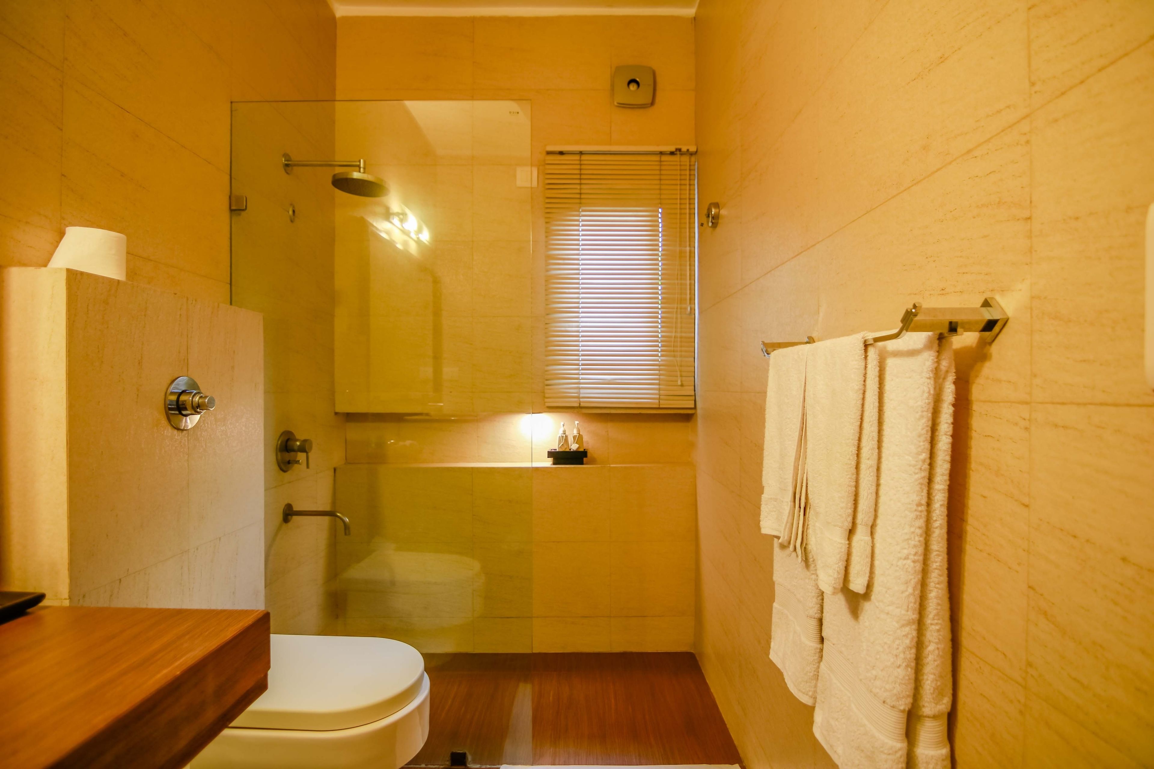 A bathroom with a glass shower enclosure, a toilet, a sink, and a towel rack.