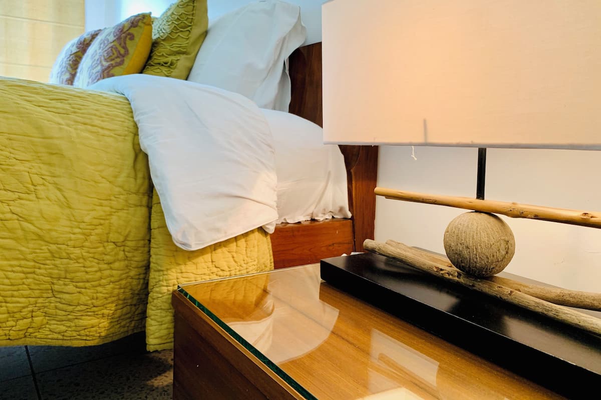 A neatly made bed with a yellow quilt, white pillows, and a wooden headboard.