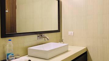 A modern bathroom with a white sink, a mirror, and a light fixture above the mirror.