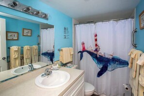 Ein Badezimmer mit einem großen Spiegel, zwei Waschbecken, einer Toilette und einer Duschvorhang mit Walmotiv.