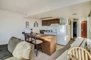 A compact living space with a kitchenette, a dining area with a wooden table and chairs, and a sofa.