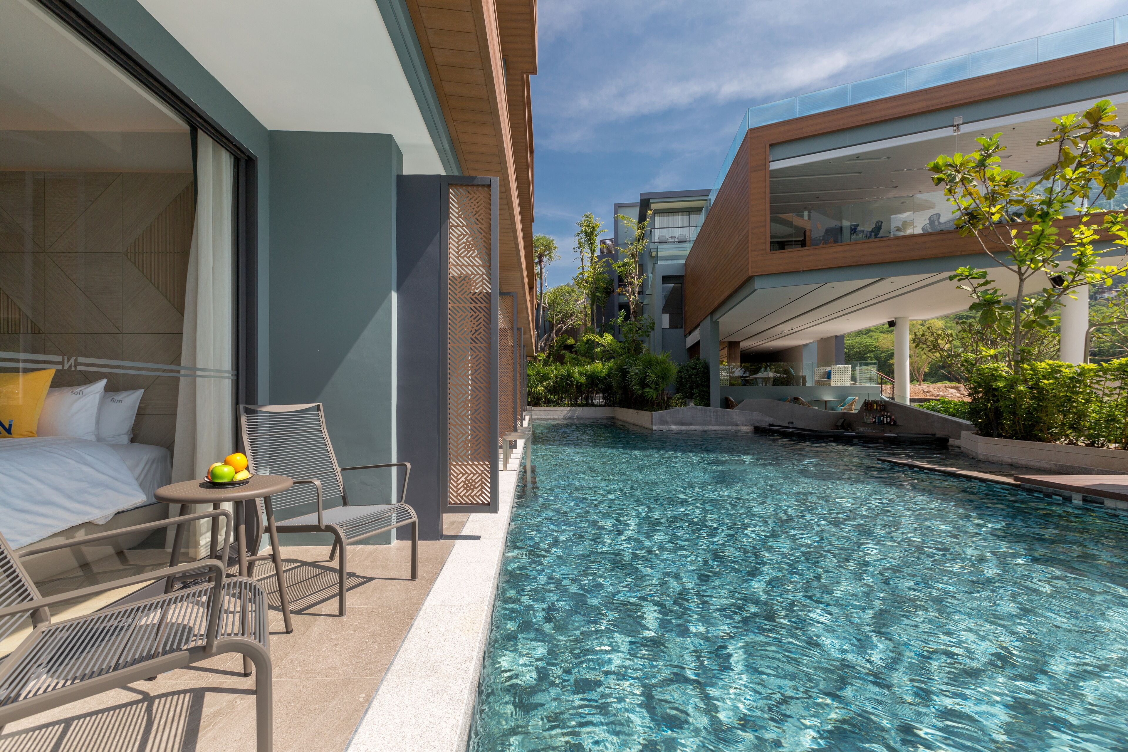 Une chambre d’hôtel moderne dotée d’une piscine privée, d’un lit, d’une petite table avec des fruits et d’un coin salon.