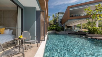 A modern hotel room with a private pool, a bed, a small table with fruit, and a seating area.