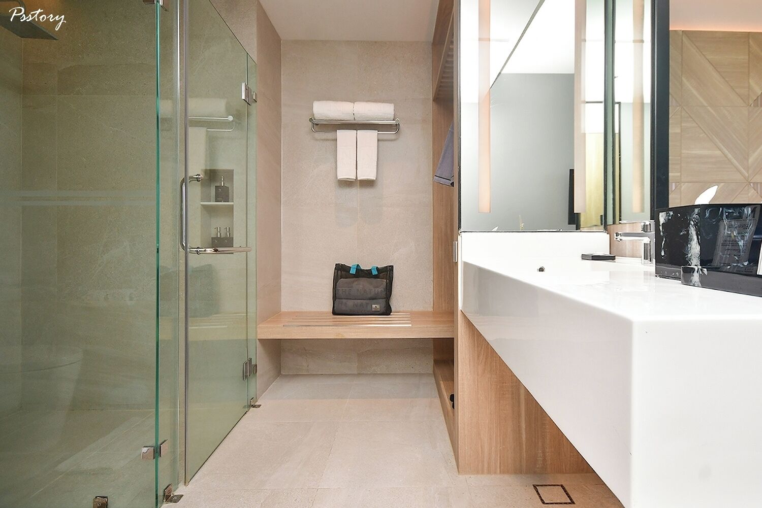A modern bathroom with a glass shower enclosure, a wooden vanity with a towel rack, and a large mirror.