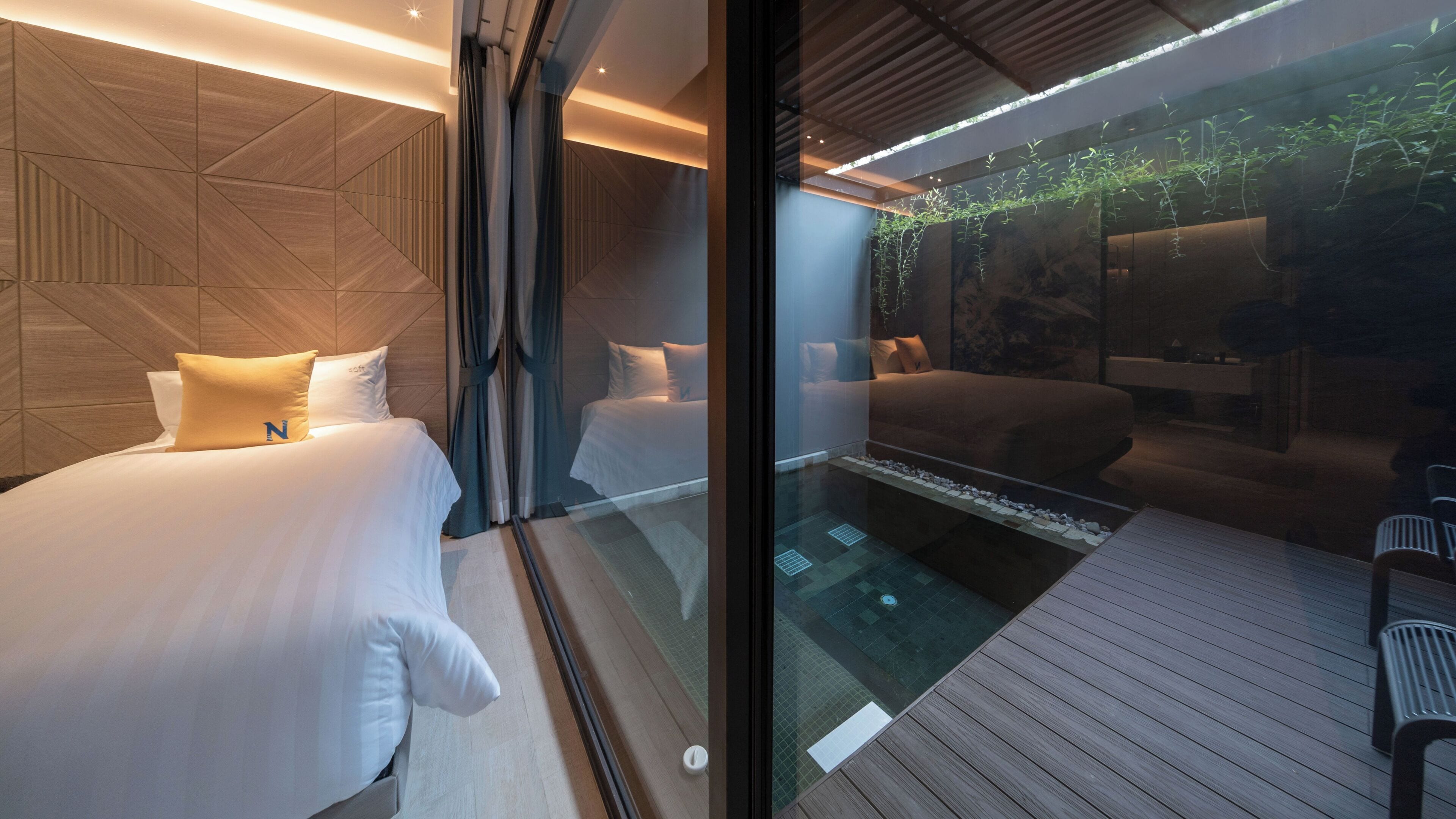 Ein modernes Hotelzimmer mit zwei Betten, einer Glaswand und einem kleinen Innenbrunnen.
