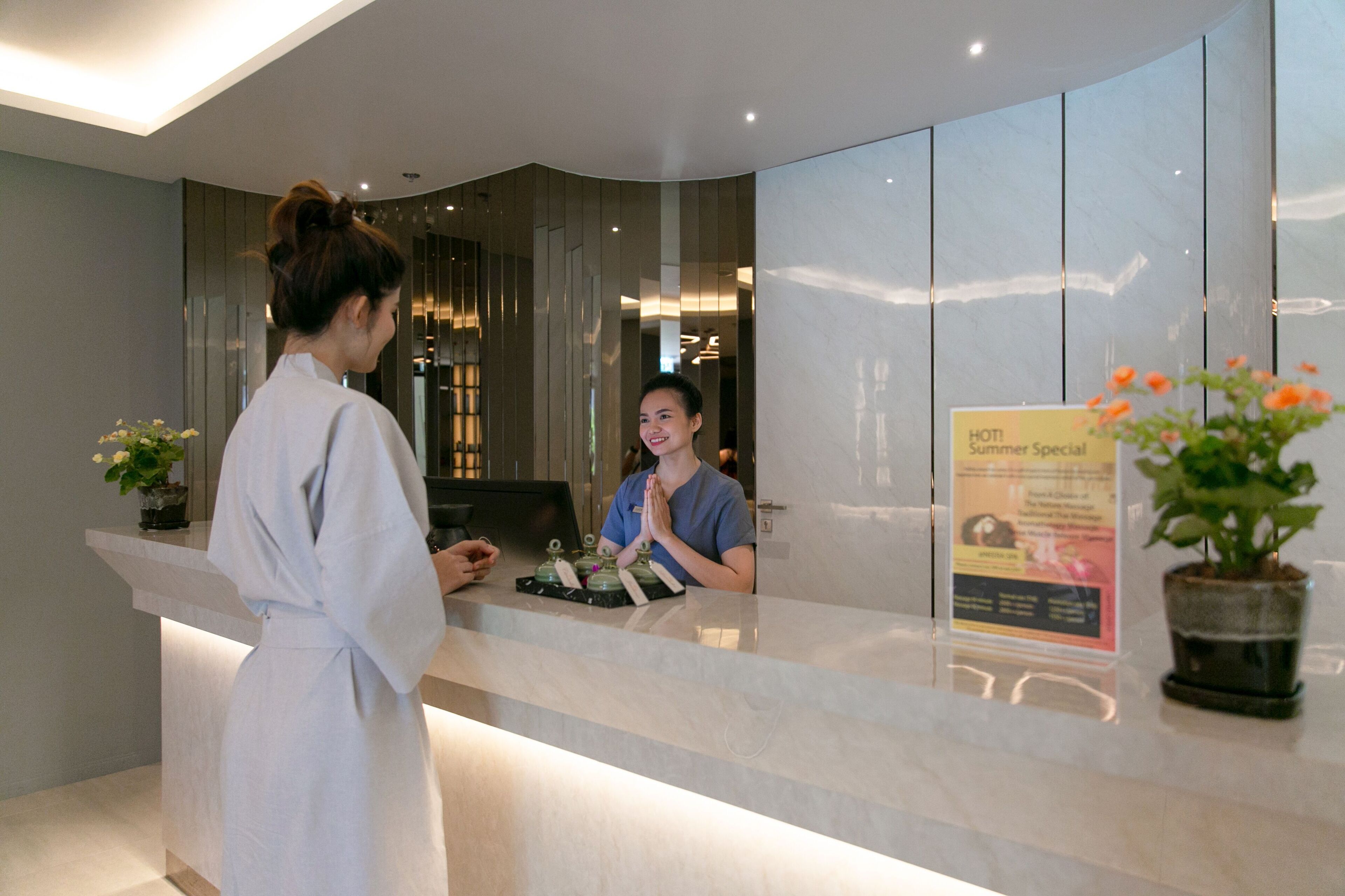 Zona de recepción de hotel con diseño moderno, un mostrador de recepción y un cartel.