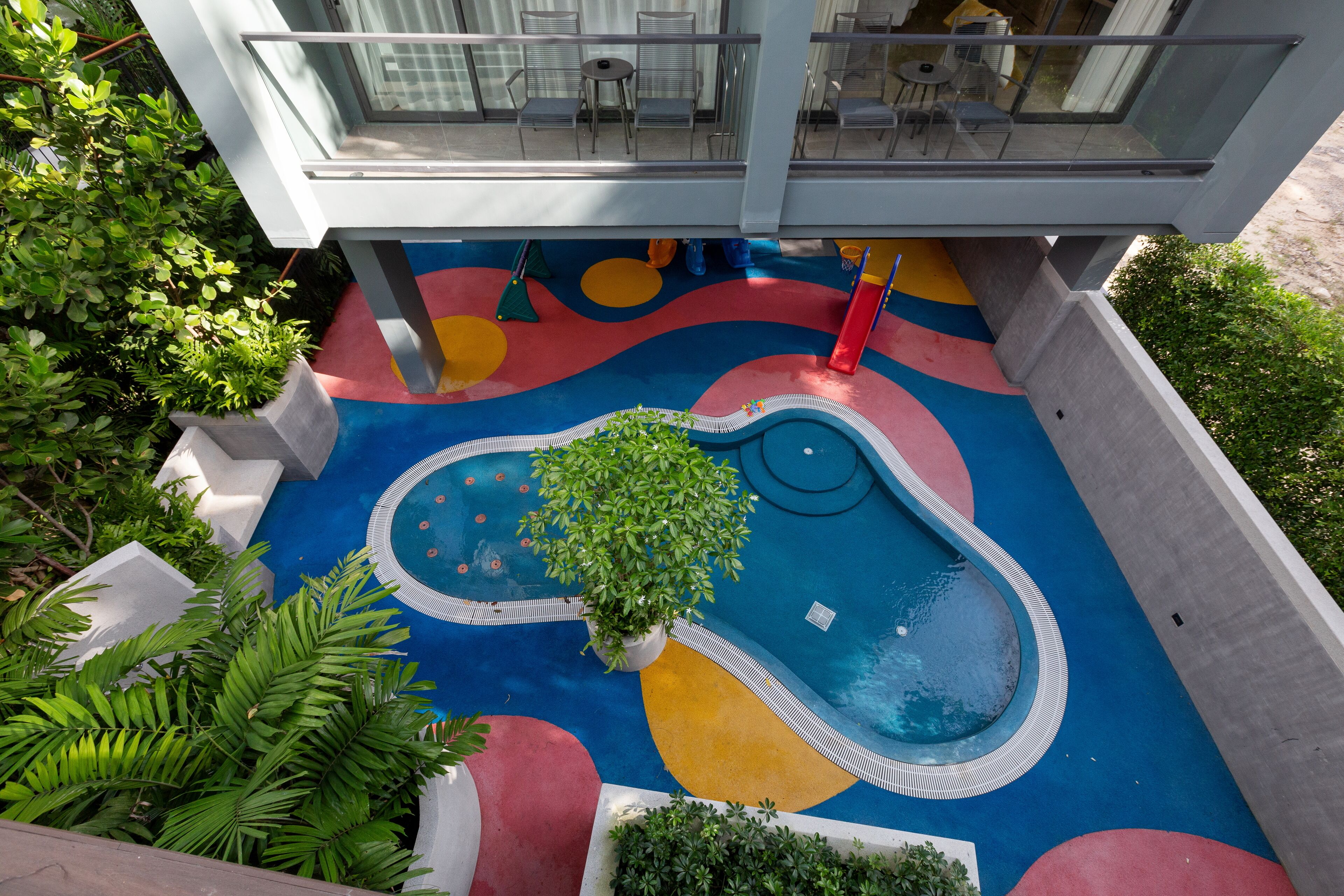 Un edificio moderno con una zona de juegos colorida y una piscina pequeña.
