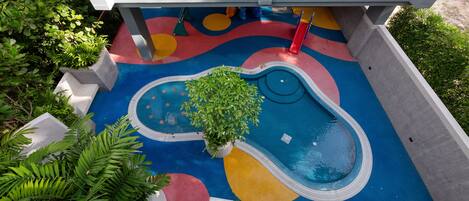 Un edificio moderno con una zona de juegos colorida y una piscina pequeña.