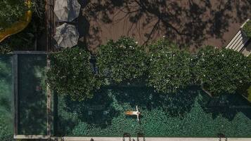 Un jardín en la azotea con piscina, zonas de estar y vistas a la ciudad.
