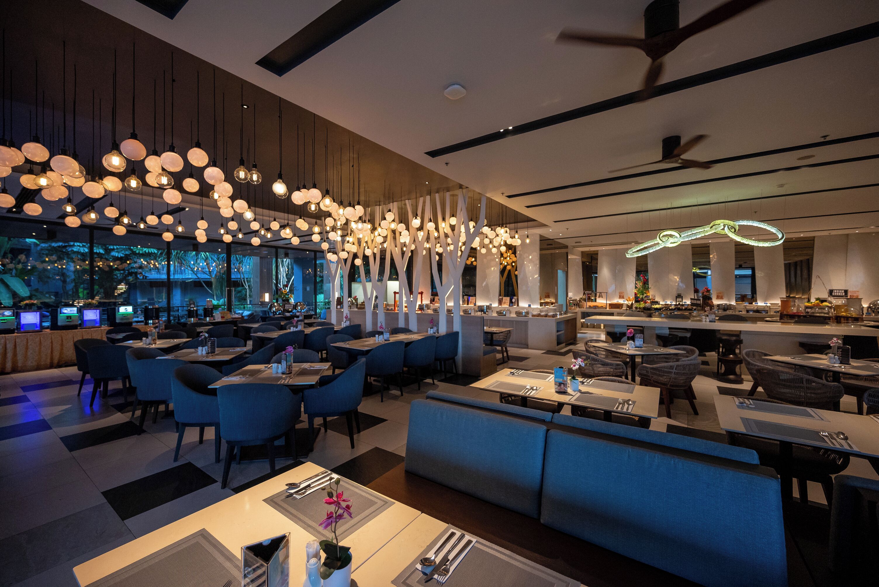 A modern restaurant with multiple seating areas, including tables and booths, and a bar area with a counter.