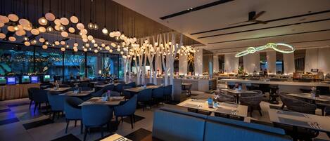 A modern restaurant with multiple seating areas, including tables and booths, and a bar area with a counter.