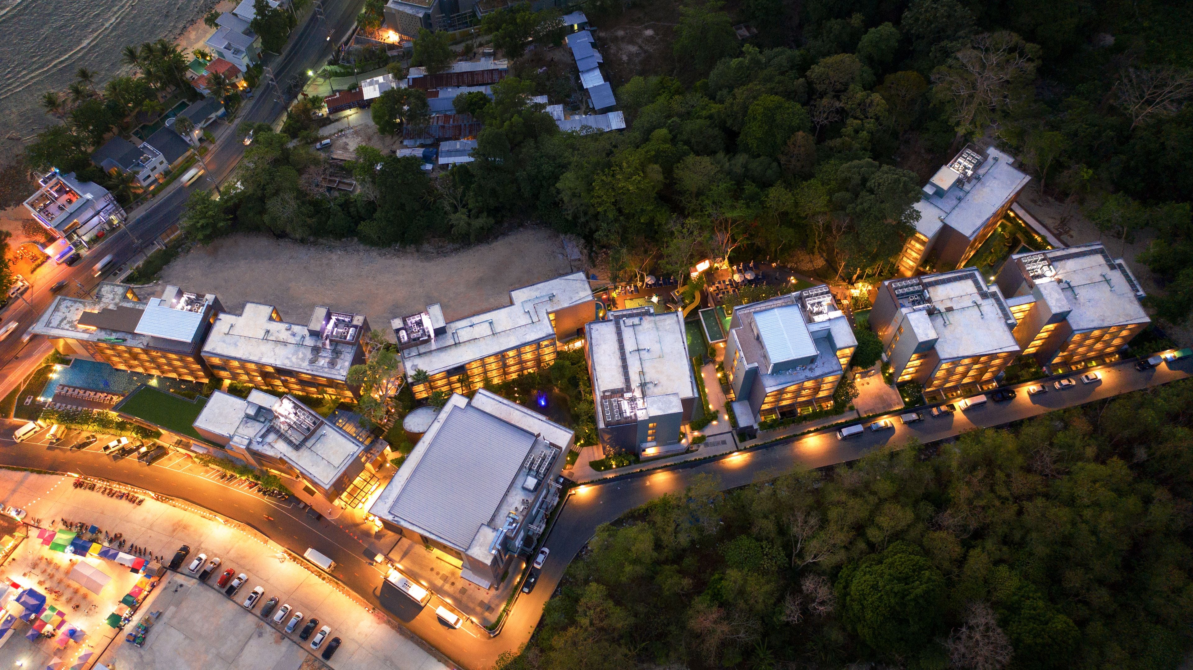 An aerial view of a hotel complex with multiple buildings, parking areas, and surrounding greenery.