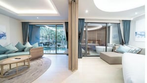 A modern hotel room with a large sliding glass door leading to a balcony, a sofa set, a small coffee table, and a separate seating area with a bathtub. - The Nature Phuket (Patong)
