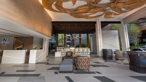 A modern lobby with a reception desk, seating area, and a unique ceiling design. - The Nature Phuket (Patong)