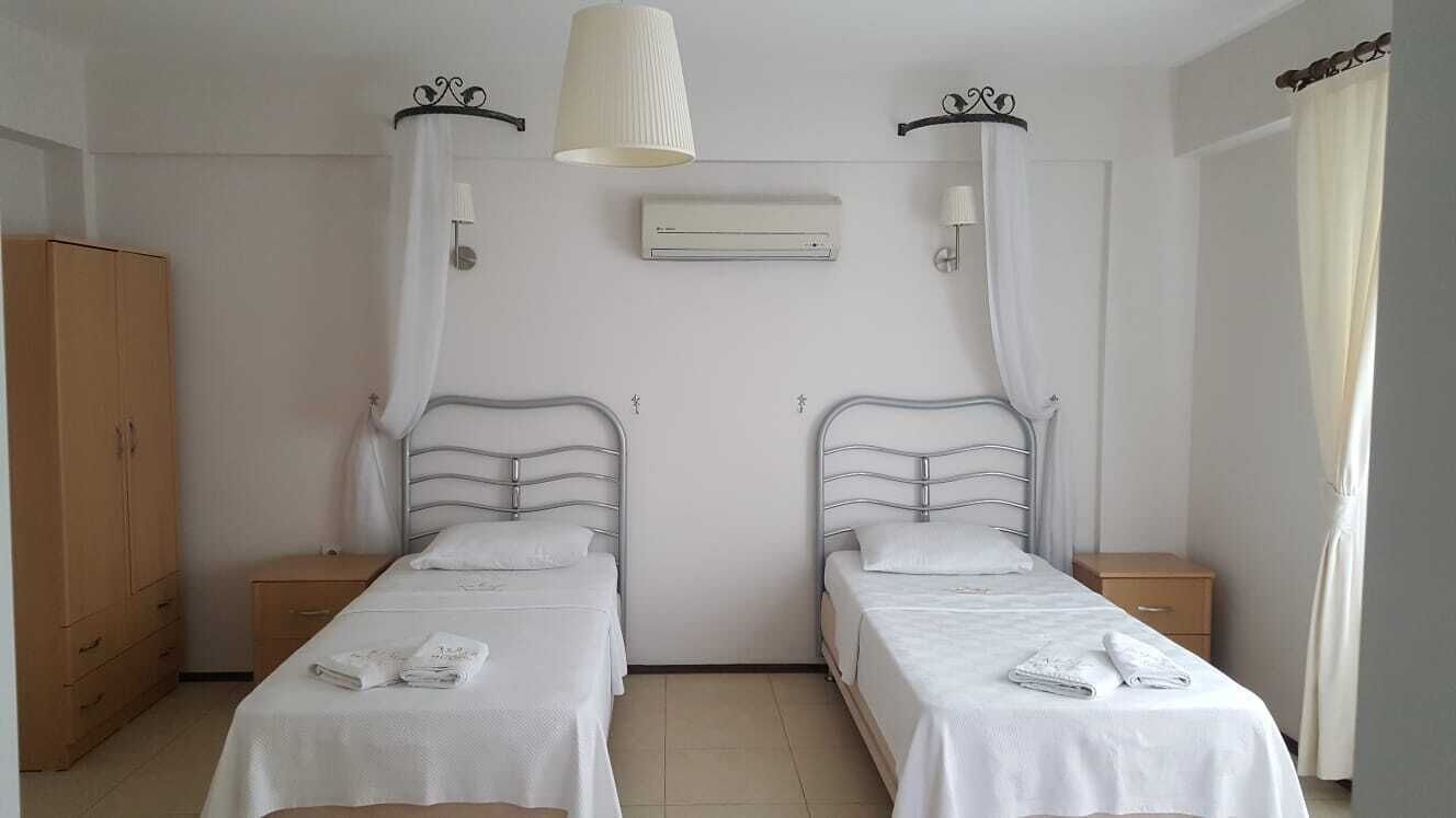 Une chambre avec deux lits simples, une armoire, un climatiseur et une lampe de chevet.