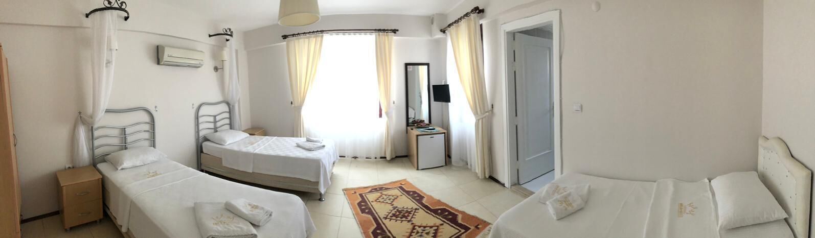 Une chambre d’hôtel avec deux lits, un petit bureau, un miroir et une porte.